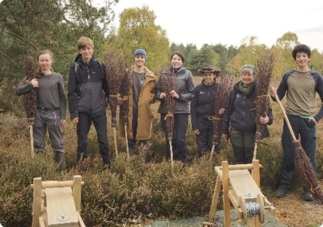 Young people pictured holding besom brooms made on the heathland during a volunteer task