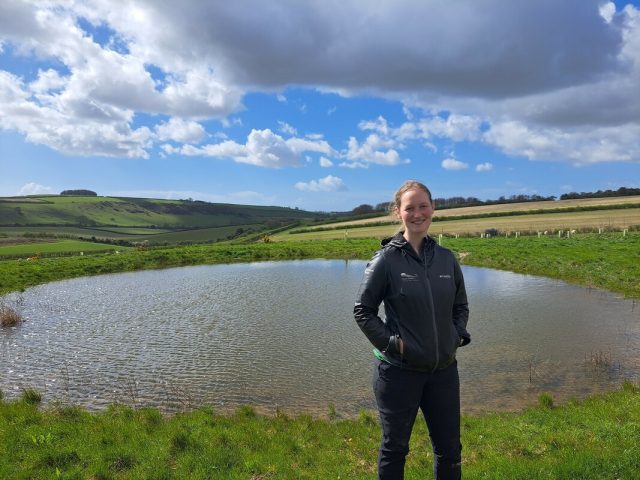 South Downs National Park ranger Sophie Brown standing by a recently restored dew pond at Peppering on the South Downs