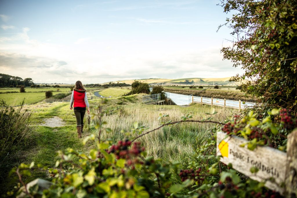 A walker follows the Egrets Way shared path along the river Ouse