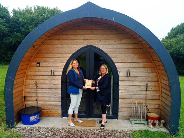 Two people receiving a Green South Downs Sustainability Certified award at Foot of the Downs glamping site in West Sussex