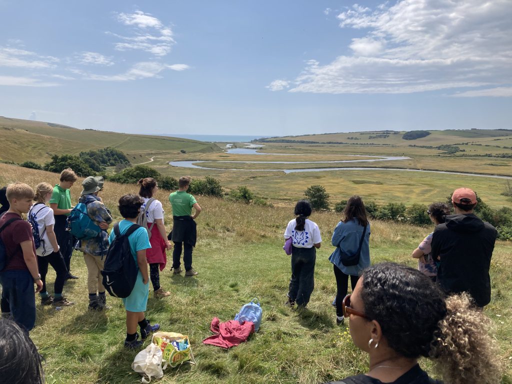 Young group of summer camp participants looking over the Cuckmere river at Seven Sisters Country Park 