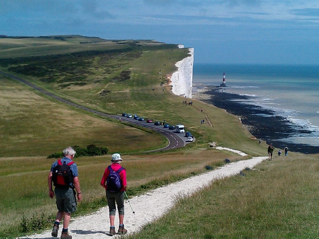 Walkers approaching Beachy head over the clifftops of the South Downs