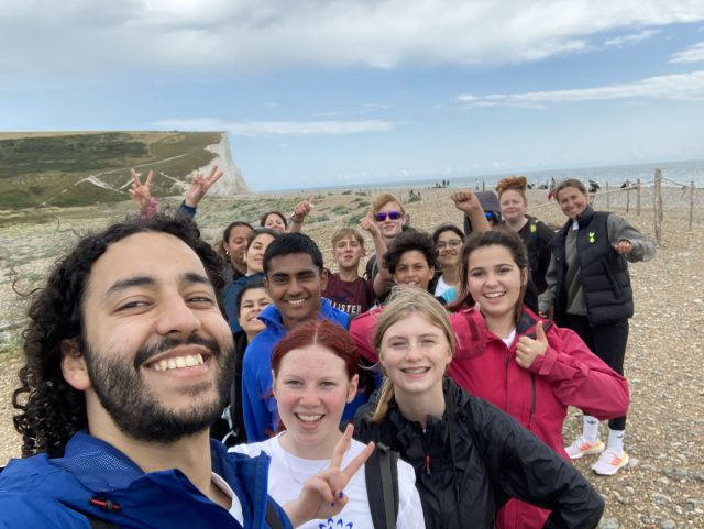 Image shows a group of young people posing for a selfie during a Youth Action Day on the beach at the mouth of the river Cuckmere at Seven Sisters Country Park in South Downs National Park